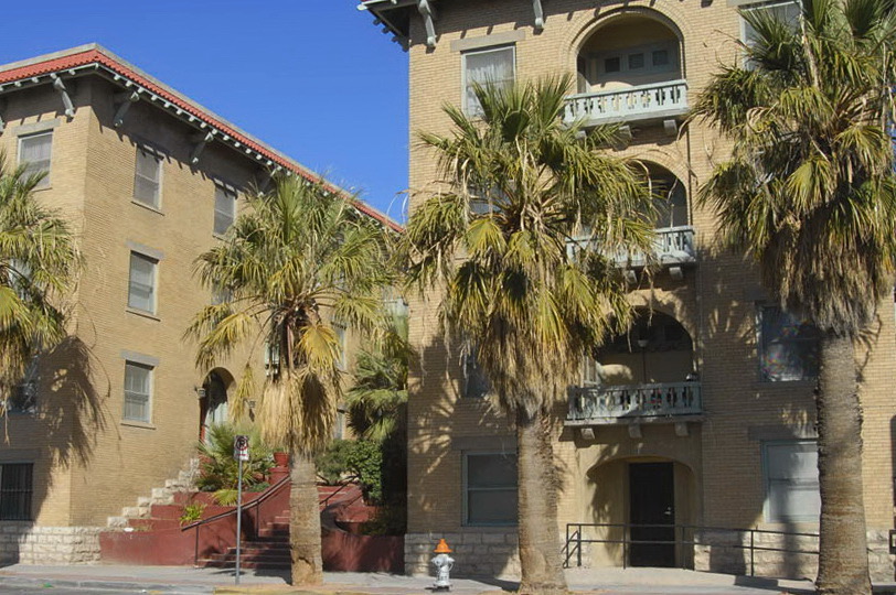 Palm Court Apartments historic brick exterior with palm trees and arched balconies